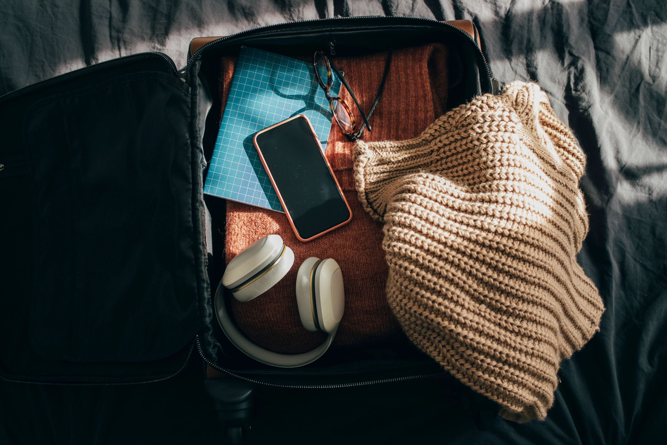 Open suitcase being packed on a bed
