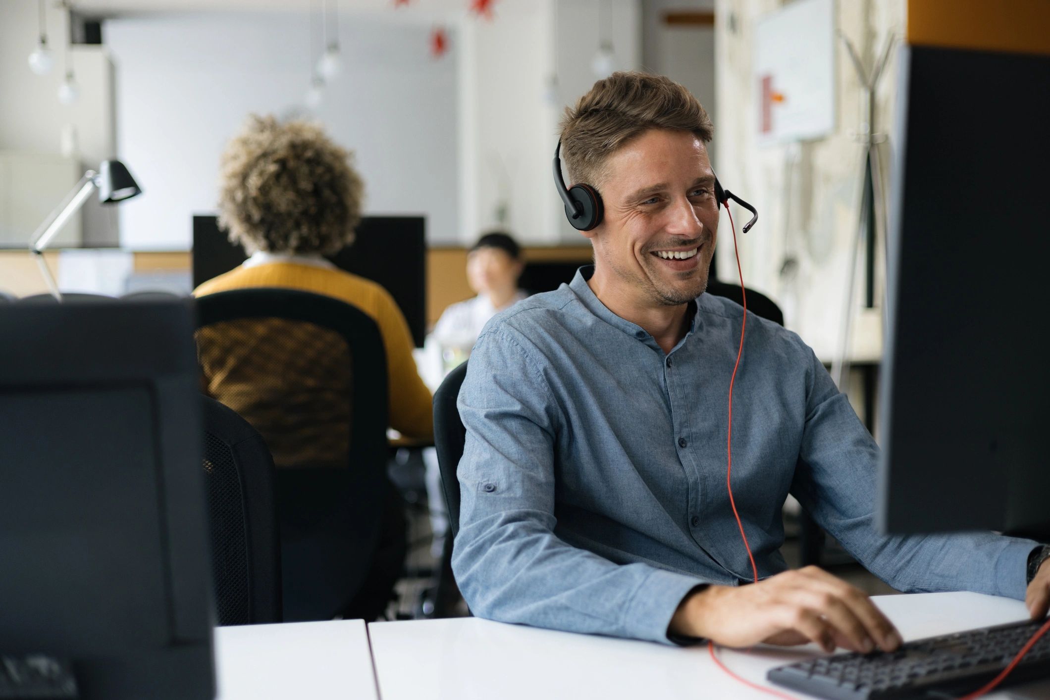 Customer support representative wearing a headset at a computer