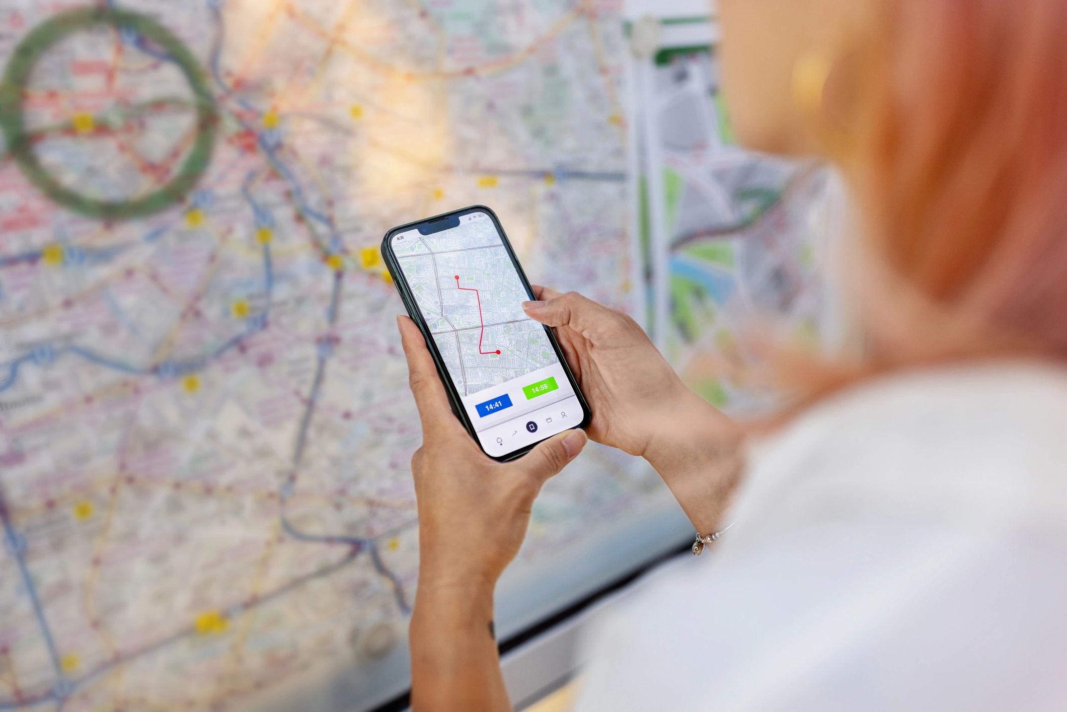 Person holding a smartphone while checking a transit map