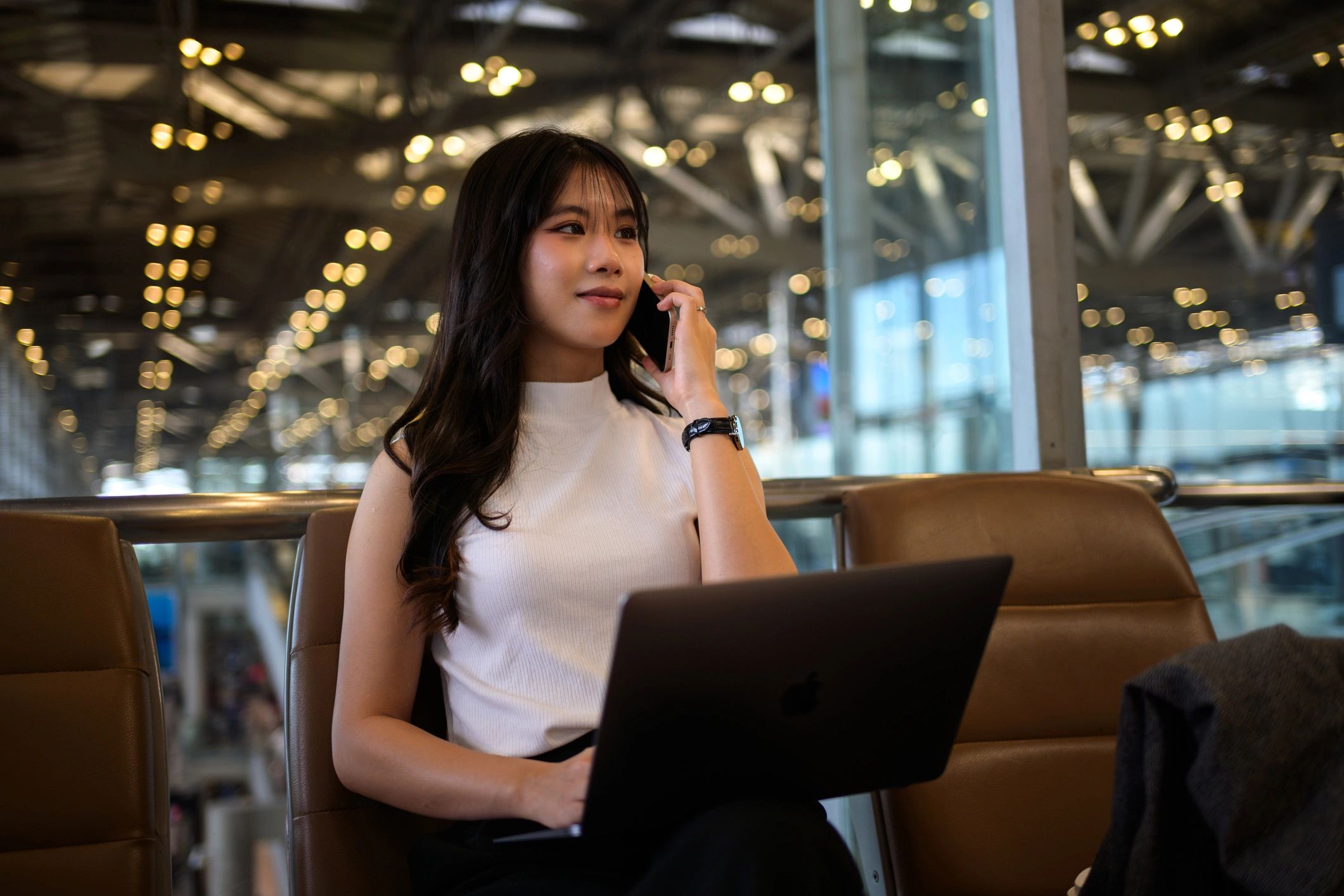 Traveler working on a laptop and phone in an airport lounge